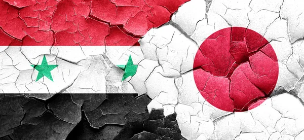 Syrien flagga med Japan flagga på en grunge knäckt vägg — Stockfoto