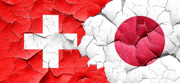switzerland flag with Japan flag on a grunge cracked wall