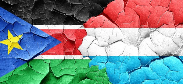 Jižní Súdán vlajky s Lucemburskem vlajku grunge popraskané zdi — Stock fotografie