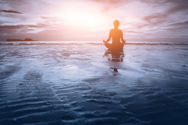 Kadın plajda yoga yapıyor.