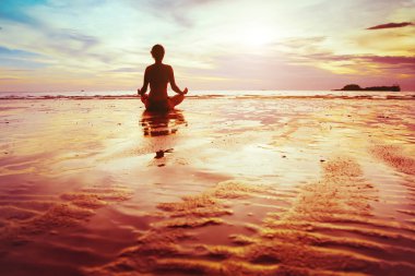 Kadın plajda yoga yapıyor.