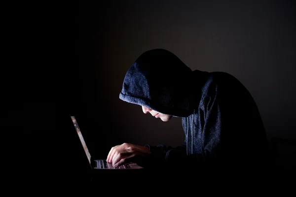 Hacker met laptop in donker — Stockfoto
