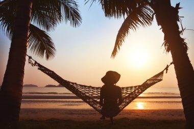 woman relaxing in hammock on beach clipart