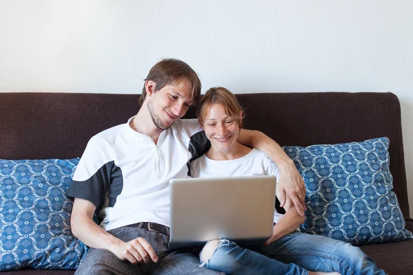 Casal sorridente com laptop em casa — Fotografia de Stock