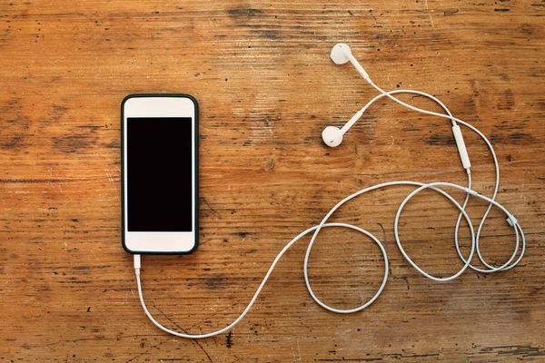 Beyaz akıllı telefon ve kulaklık — Stok fotoğraf
