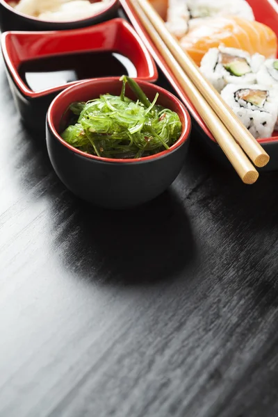 Seaweed salad and sushi assortment on plate with chopsticks