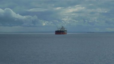 Bir kargo gemisi bulutlu ve sakin bir denizde seyahat eder.