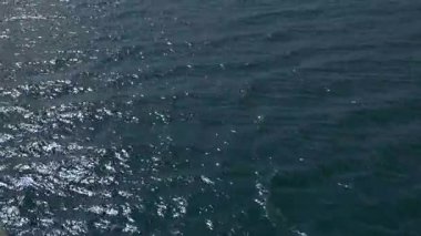 Mavi denizin yüzeyi güneşin yansımaları sayesinde parlıyor. Suyun yüzeyinde bir ışık yolu oluşturuyor..