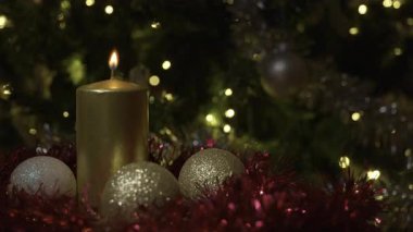 Ortasında parlak gümüş bir mum olan Noel çelengi ve etrafında altın süslemeler