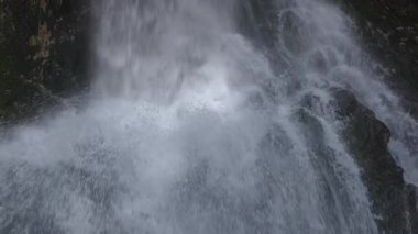 Şelaleden düşen ve kayalara çarpan su akıntılarının yakın çekim görüntüsü.