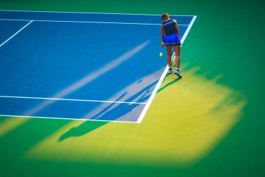 Kortta tenis oynayan genç bir kadın.