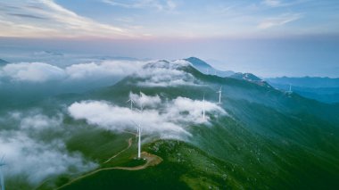Yel değirmenleri ve alçak bulutlu yeşil dağ manzarası