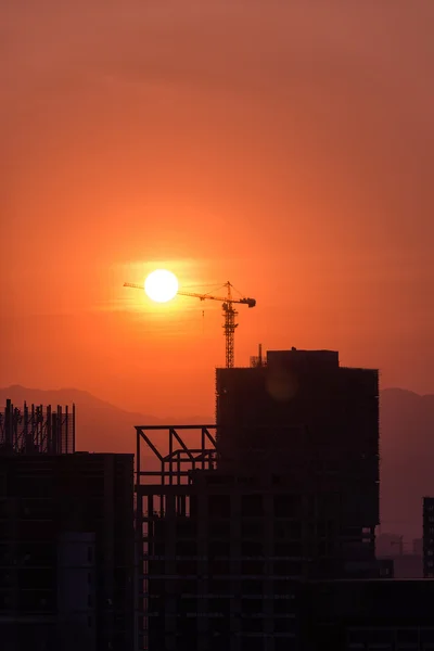 Guindastes de construção industrial e silhuetas de construção sobre o sol — Fotografia de Stock