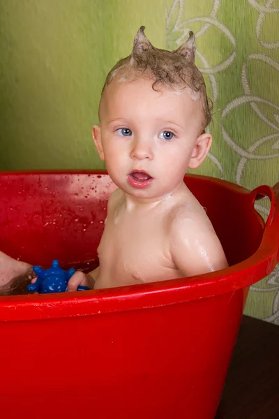 Cute little blond girl sitting in a bathtub with soap head Royalty Free Stock Images