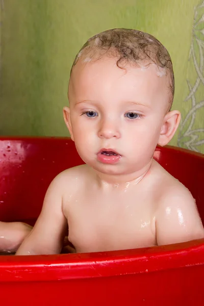 Beautiful little blond girl sitting in the bathroom and chew toys Stock Picture