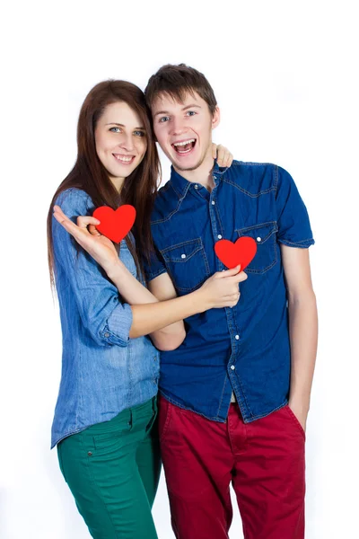 Belo jovem casal segurando um pequeno coração de papel vermelho nas mãos — Fotografia de Stock