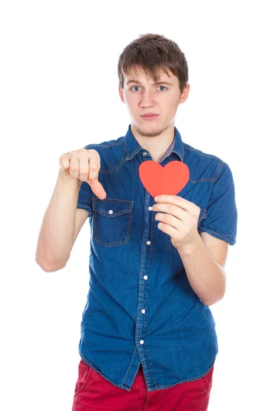 Bel giovanotto in denim camicia blu in piedi su uno sfondo bianco con un cuore di carta rossa in mano . — Foto Stock