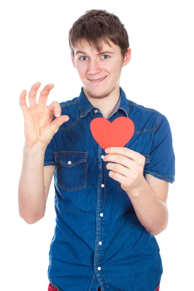 Stilig ung man i denim blå skjorta står på en vit bakgrund med röd papper hjärta i händer. — Stockfoto