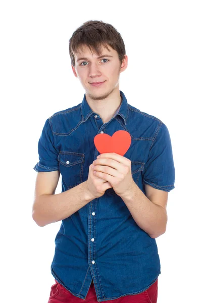 Stilig ung man i denim blå skjorta står på en vit bakgrund med röd papper hjärta i händer. — Stockfoto