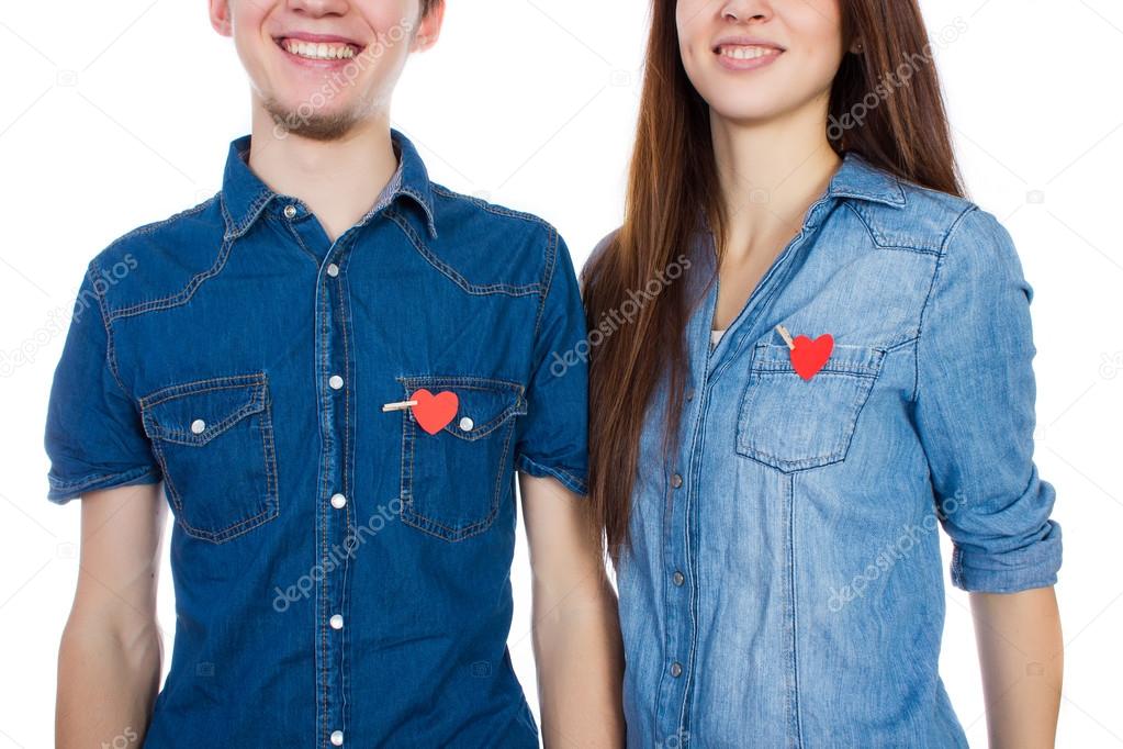 Miling couple standing isolated on white background with paper  heart in pocket.