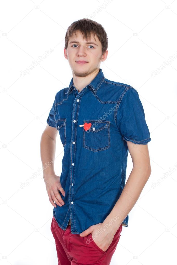 Attractive boy standing isolated on white background with a red paper heart in his pocket.