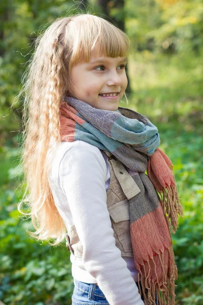 Beautiful little young baby stands in a scarf. Lovely  child smiling — Stock Photo, Image