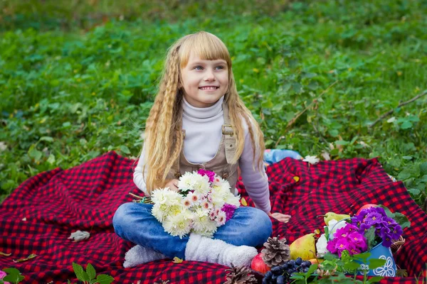 Beautiful little young baby sitting  on a red plaid. Lovely   child smiling with bright flowers — Stock Photo, Image