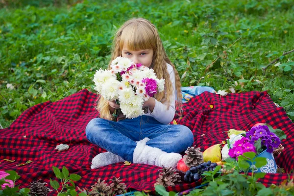 Beautiful little young baby sitting  on a red plaid. Lovely  child smiling with bright flowers — Stock Photo, Image