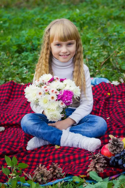 Beautiful little young baby sitting  on a red plaid. Lovely  child smiling with bright flowers — Stock Photo, Image