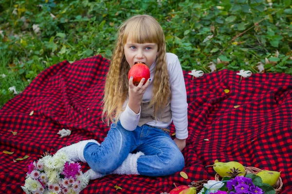 Красивый маленький ребенок в розовой шляпе с яблоком в руке. Красивый ребенок сидит на красной клетке . — стоковое фото