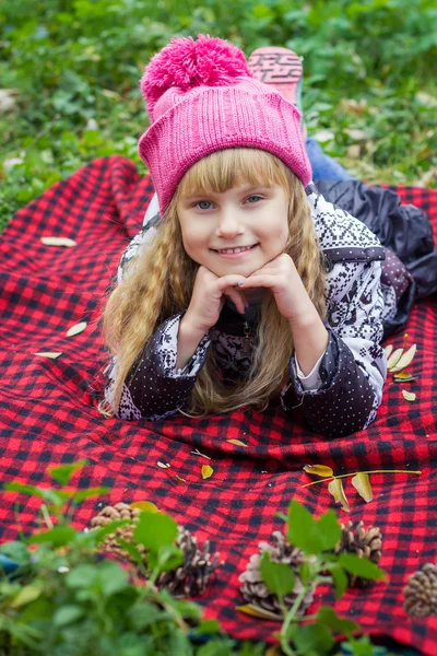 Beau petit bébé au chapeau rose. Bel enfant repose sur un plaid rouge — Photo