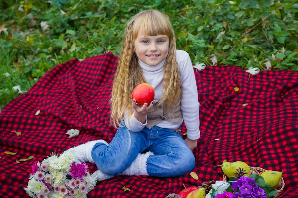 Mooie kleine jonge baby in een roze hoed met een appel in zijn hand. Mooi kind zittend op een rode plaid. Rechtenvrije Stockfoto's