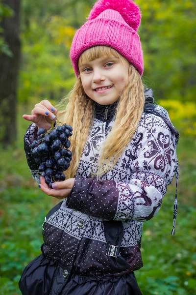 Mooie kleine jonge baby in een roze hoed met druiven in hun handen Stockfoto