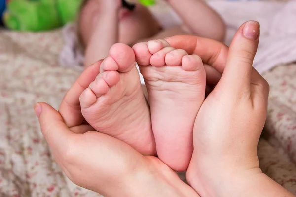 Mãe gentilmente segure a perna do bebê na mão. Imagem de cor bonita com foco suave no pé do bebê — Fotografia de Stock