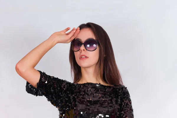 Beautiful brunette girl in a black dress and sunglasses. Brunette with long black hair — Stock Photo, Image