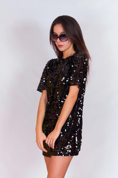 Beautiful brunette girl in a black dress and sunglasses. Brunette with long black hair. — Stock Photo, Image