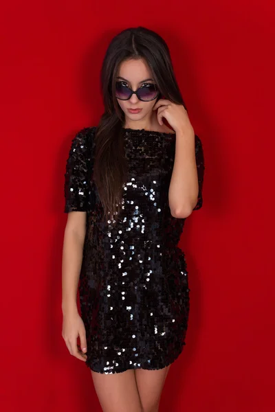 Beautiful brunette girl in a black dress and sunglasses. Brunette with long black hair — Stock Photo, Image