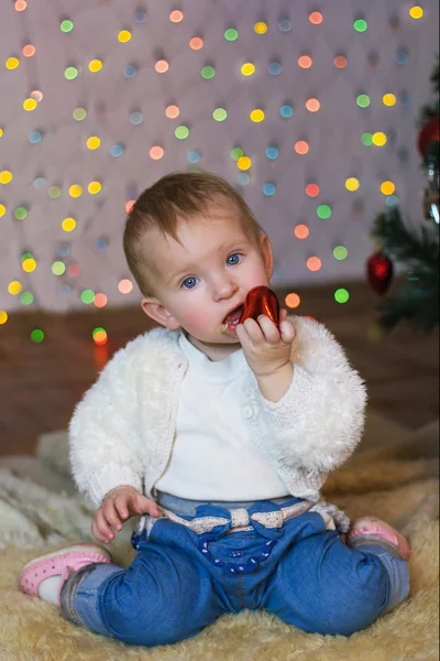 Krásná holčička v červených šatech v nový rok s úsměvem a držení dárek — Stock fotografie