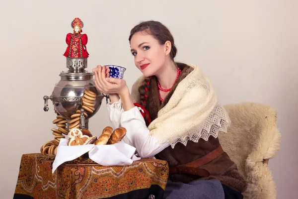Glimlachend dromen landelijke vrouw met bagels en kopje tee in omslagdoek in New Year's Eve. Stockfoto