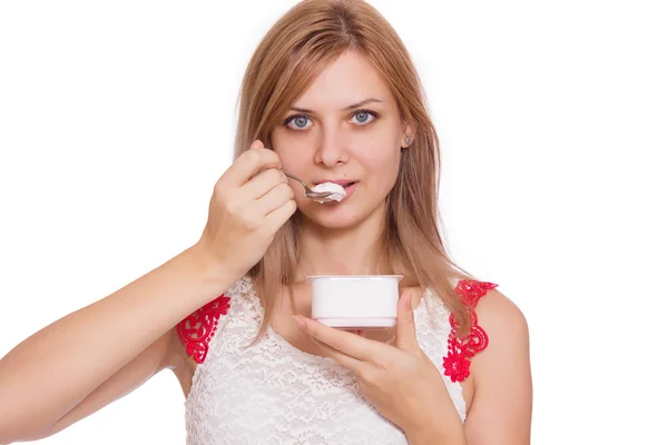 Portrait of a smiling young woman eating yogurt isolated — Stock Photo, Image