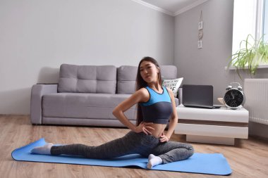 Genç Asyalı kadın evde yoga yapıyor. Carantin ve hobi. Ev izolasyonu. Online eğitim. Yumuşak odak
