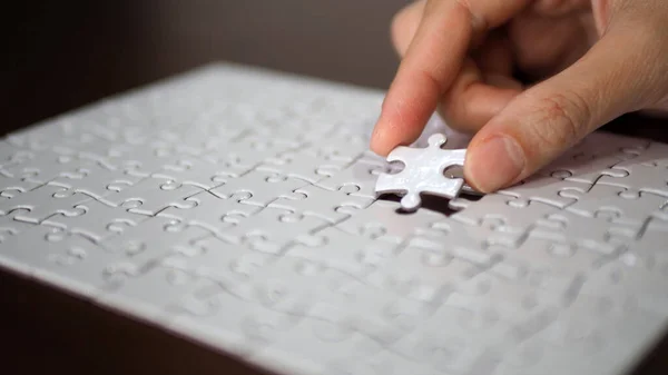 hand pick a piece of jigsaw to connect success on wooden table top selected focus