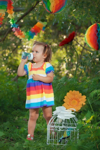 Cute little girl wearing colorful dress  drinking water — Stock Photo, Image