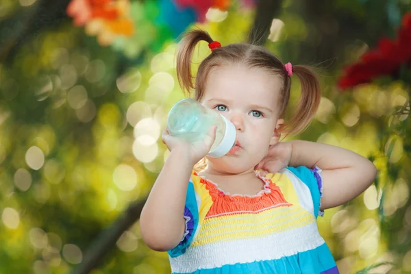 Bonito menina vestindo vestido colorido água potável — Fotografia de Stock