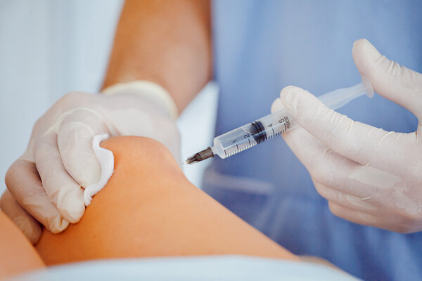 Doctor orthopedist making injection an injection into the knee
