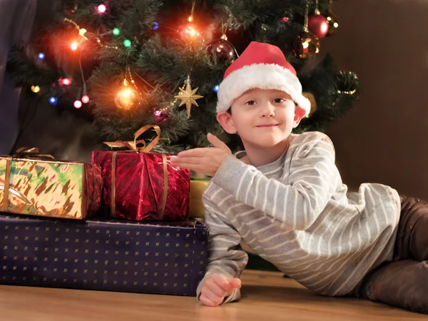 クリスマス ツリーの近くサンタ帽子をかぶって素敵な少年 — ストック写真