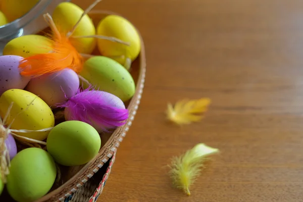Wooden basket full of colorful eggs and bird