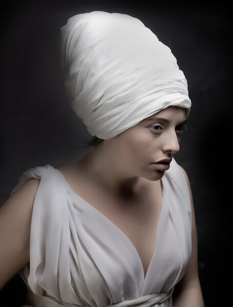 Pregnant woman dressed in a turban and draped in white fabric.It is looking like a statue