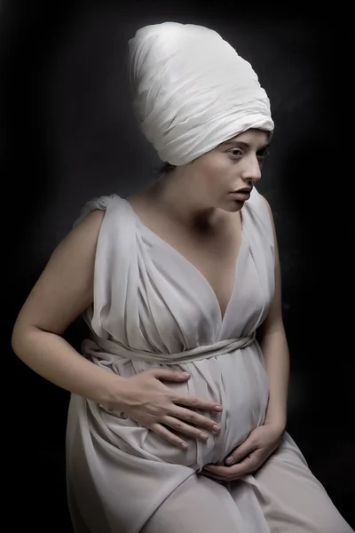 Femme enceinte vêtue d'un turban et drapée de tissu blanc . — Photo