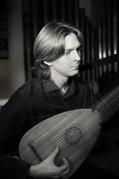 Handsome young man playing antique lute — Stock Photo, Image